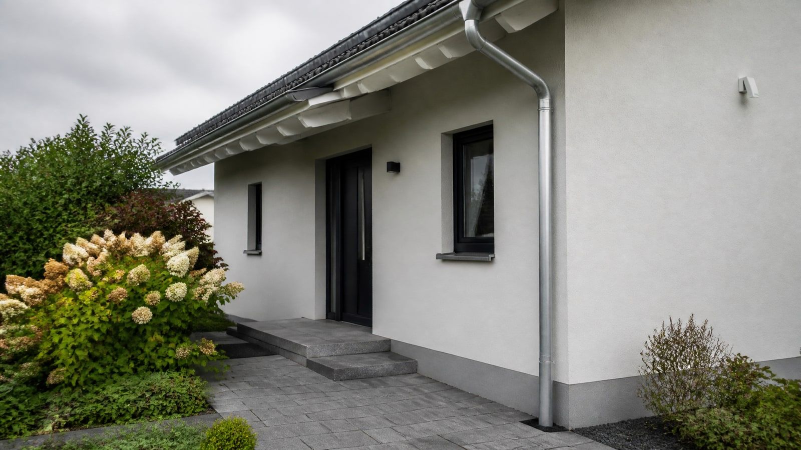 Hauseingang mit Vorgarten, Dachrinne und Fallrohr an der Fassade