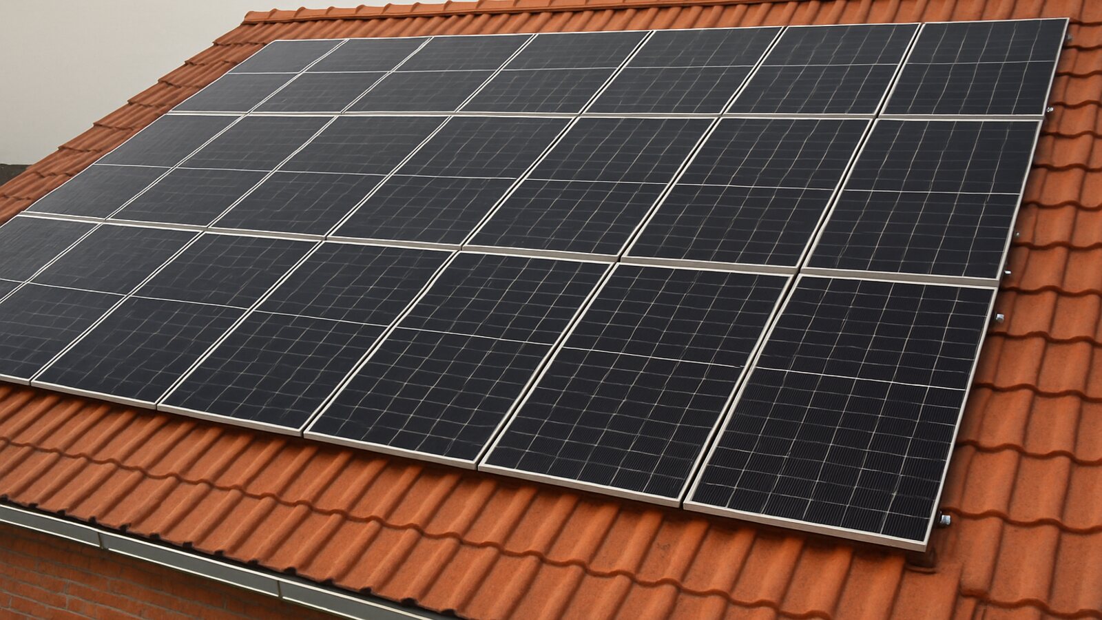 Photovoltaik Dorsten: Aufsicht auf ein fertig montiertes Feld schwarzer Solarmodule in gleichmäßigen Reihen auf einem roten Ziegeldach