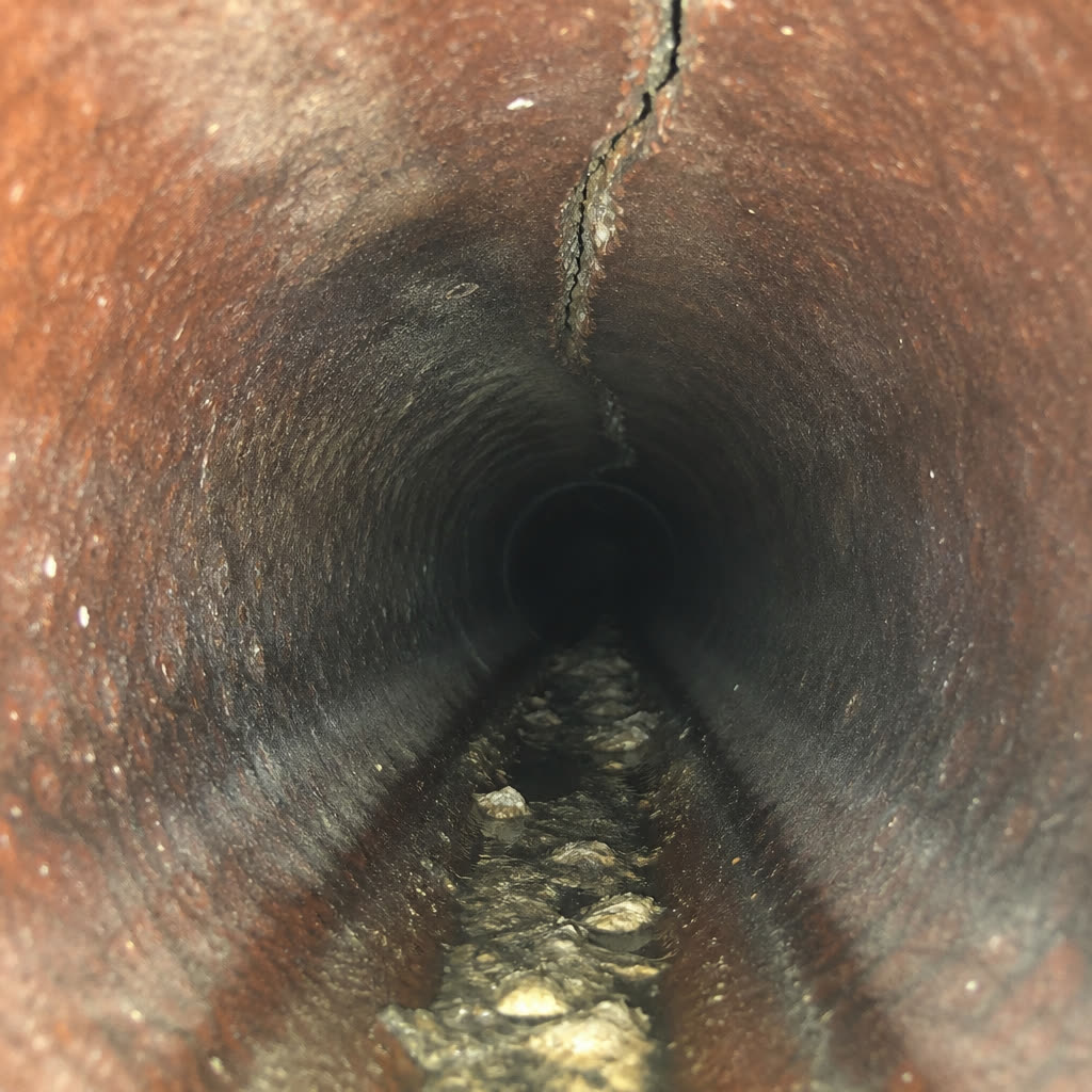 Längsriss in einem alten Steinzeug-Abwasserrohr mit Ablagerungen an der Rohrsohle
