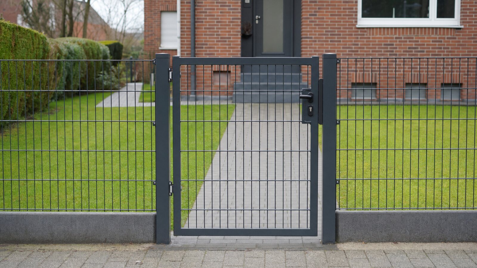 Zaunbau Herne: schmale anthrazitfarbene Metall-Gehpforte mit anschließendem Doppelstabmattenzaun am Backstein-Siedlungshaus