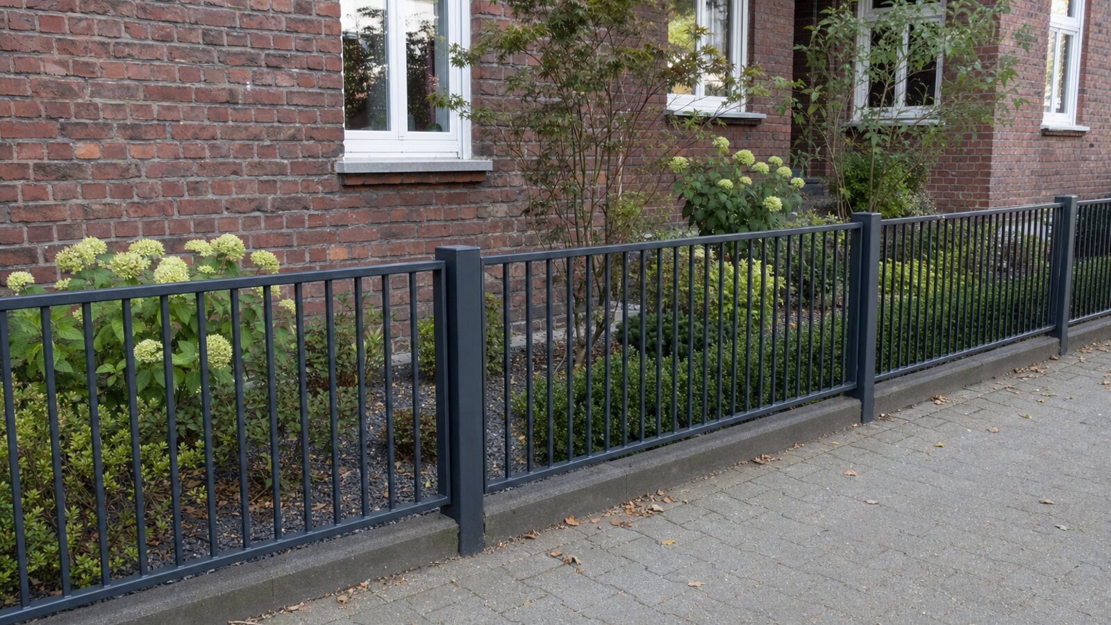 Zaunbau Herten: anthrazitgrauer Metallstabzaun mit zwei Querriegeln am Vorgarten eines Backsteinhauses
