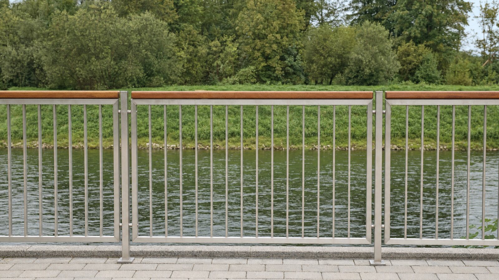 Zaunbau Leichlingen: Geländerzaun aus Edelstahl-Flachstäben mit Holz-Handlauf auf einer Uferterrasse mit Blick auf die Wupper