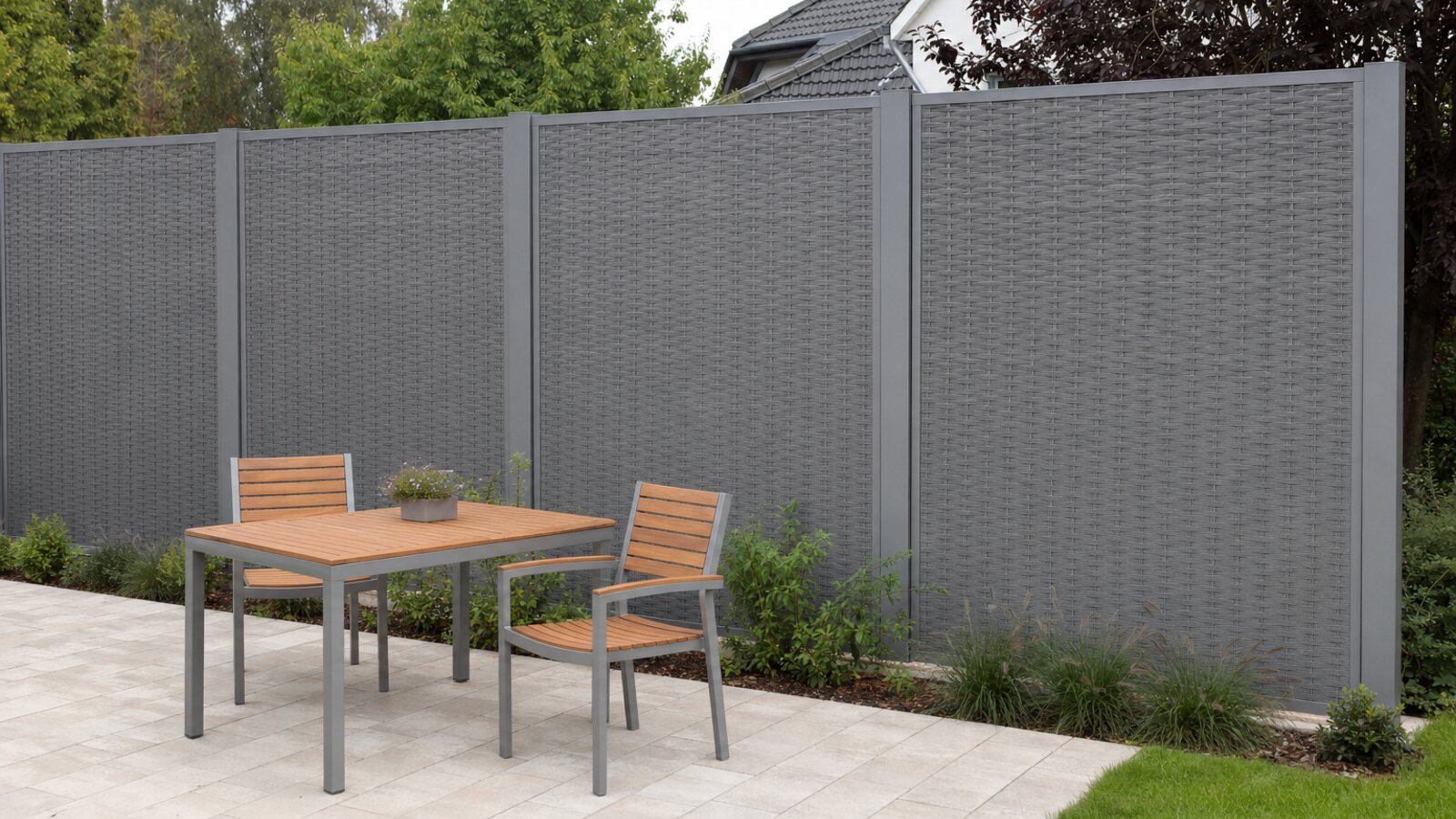 Zaunbau Marl: grauer Sichtschutz aus geflochtenem Kunststoff-Rattan in Aluminium-Rahmen zwischen Pfosten um eine Gartenterrasse