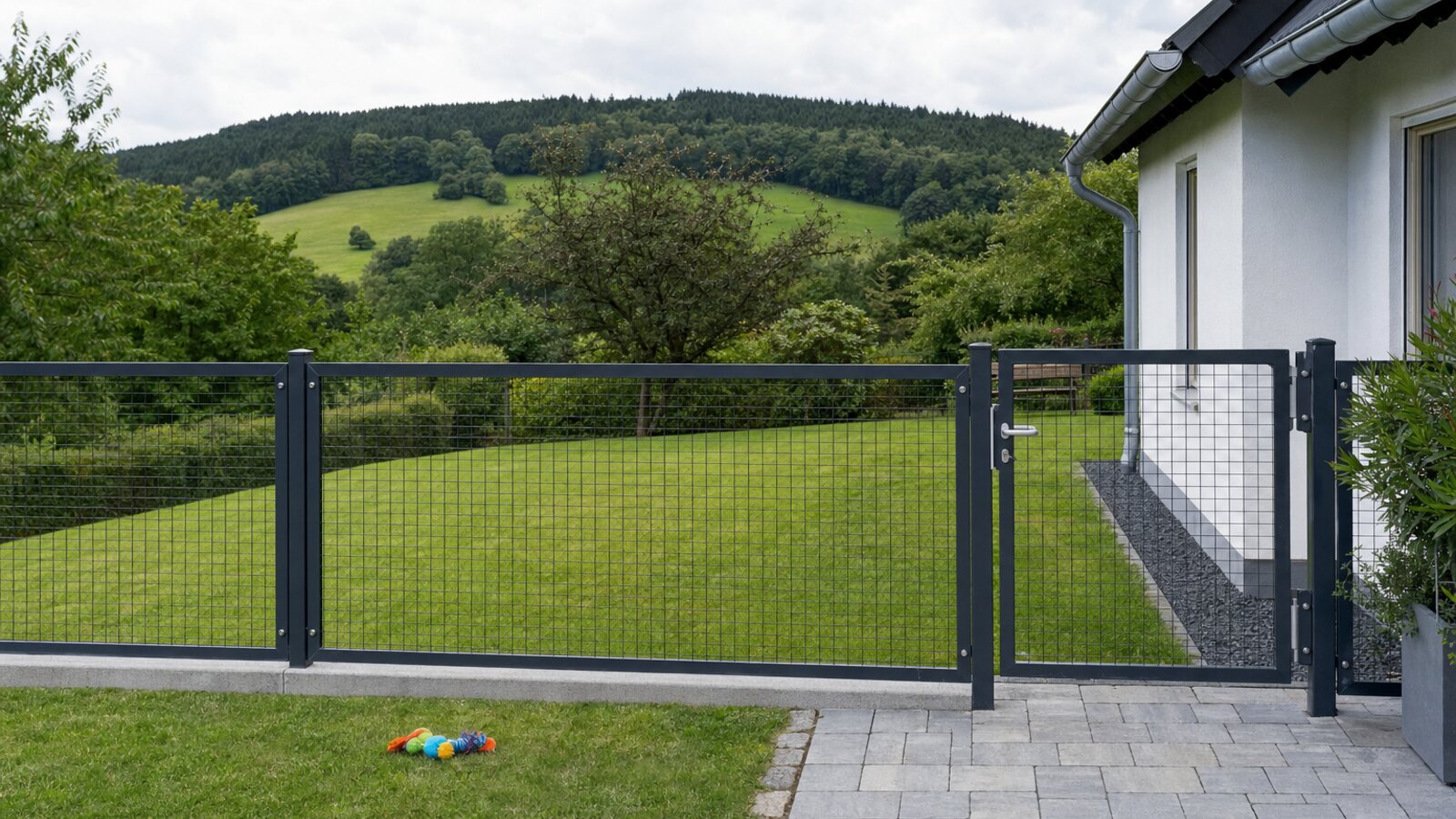 Zaunbau Oer-Erkenschwick: Hundeauslauf mit anthrazitfarbenen Gitterzaunfeldern auf Betonkante und abschließbarer Gartenpforte am Wohnhaus